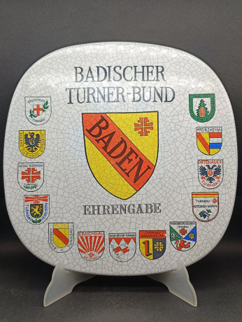 Тарелка декоративная винтажная Im Stil Karlsruhe Majolika "Ассоцияция гимнатики Бадена", сувенирная, квадратной формы, с эффектом кракелюра, фарфор, 30.5 см, Германия, 1974 год.