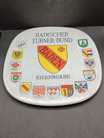 Тарелка декоративная винтажная Im Stil Karlsruhe Majolika "Ассоцияция гимнатики Бадена", сувенирная, квадратной формы, с эффектом кракелюра, фарфор, 30.5 см, Германия, 1974 год.