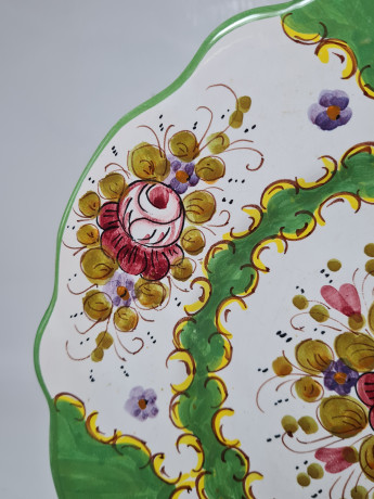 Тарелка винтажная декоративная Im Stil von Italy с округлым цветочным декором, в зеленовато-красных тонах, с фигурным краем, керамика, ручная роспись, 25.5 см, Италия, 1960-70гг.